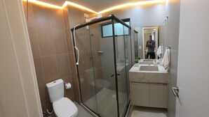 A modern bathroom with a glass-enclosed shower, a toilet, and a vanity with a sink. - Porto Baobas Vista Mar 102 By LP (Ipojuca)