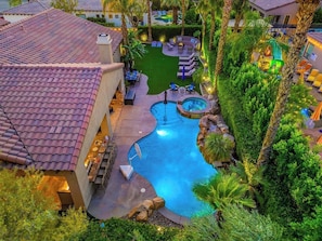 A swimming pool surrounded by palm trees and lounge chairs, with a patio area and a view of a building. - Boss Mode/Pickleball/Gameroom (Indio)