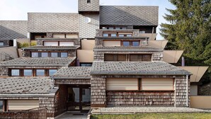 Un moderno edificio residenziale con diversi livelli, un tetto spiovente e una piccola struttura simile a una torre.