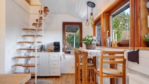 Una cucina con una scala in legno, un tavolo da pranzo con sedie, una finestra vista e un armadietto bianco.