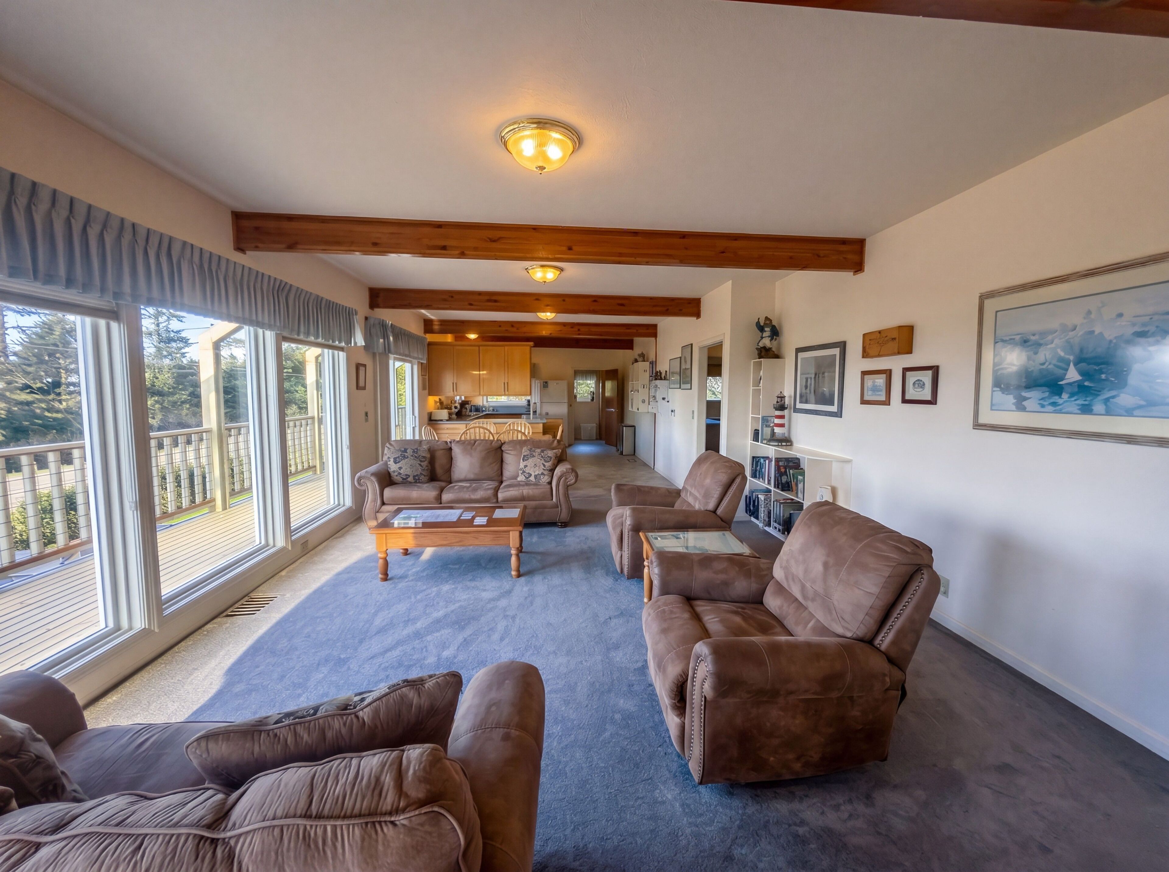 A spacious living area with a large window, a kitchen in the background, and a dining area.