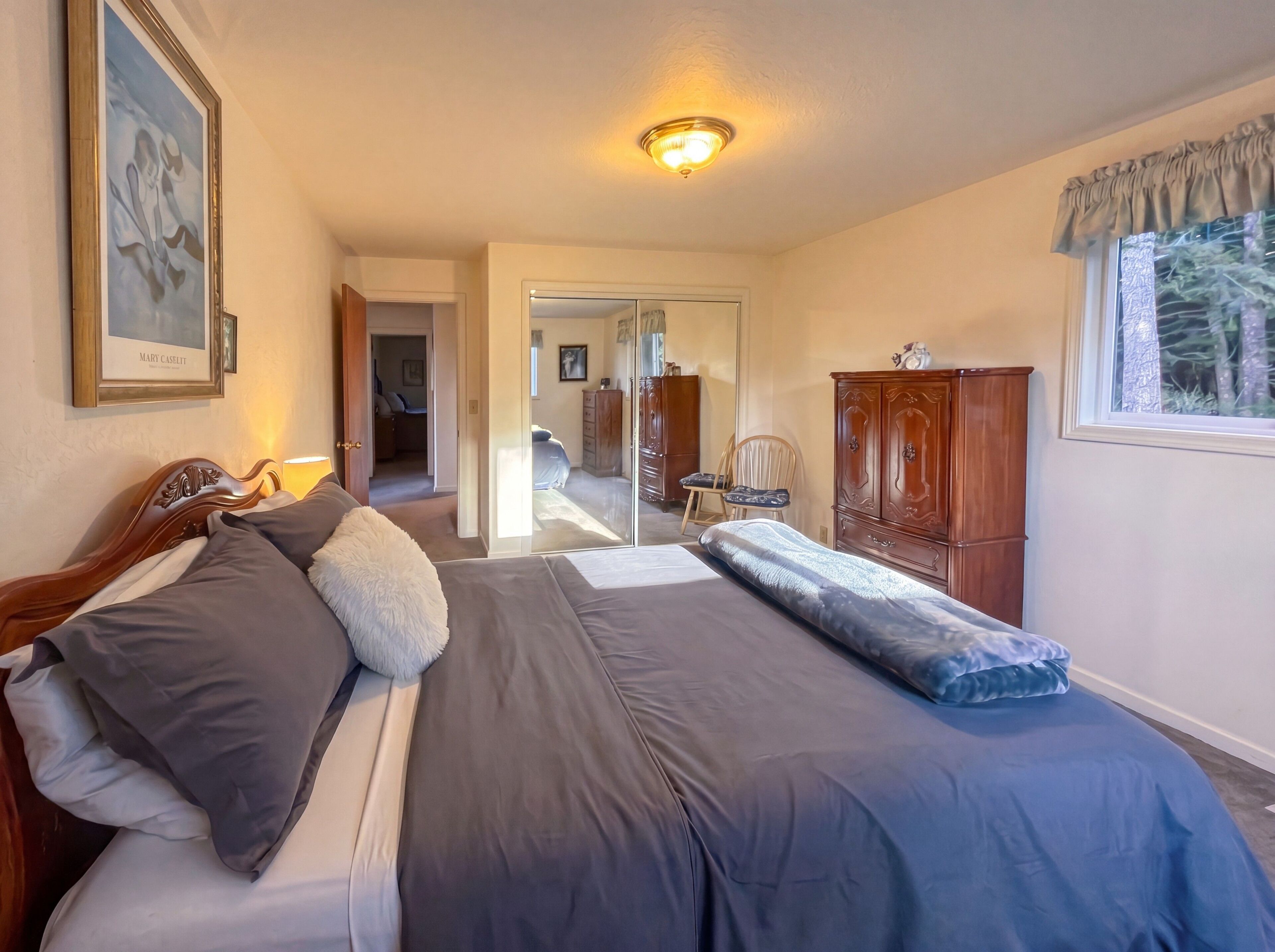 Une chambre à coucher avec un lit, une armoire en bois, une fenêtre avec des rideaux et un couloir menant à une autre pièce.