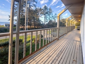 A wooden deck with a railing, overlooking a road and greenery. - Ocean View Retreat on 2 acres (Coos Bay)
