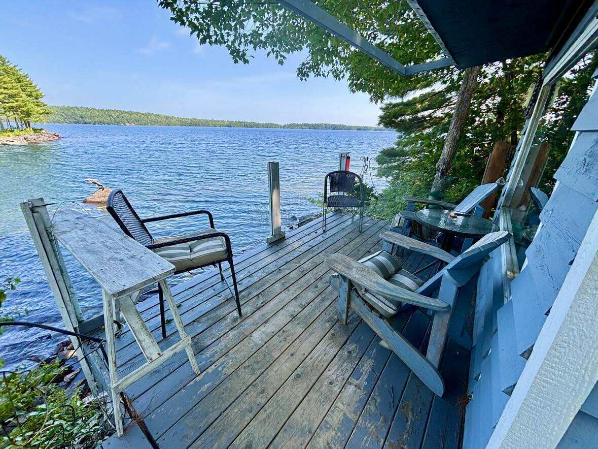 A wooden deck with a table and chairs overlooking a lake.
