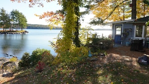 Un chalet au bord du lac, doté d’un quai, et entouré d’un paysage automnal aux couleurs flamboyantes.