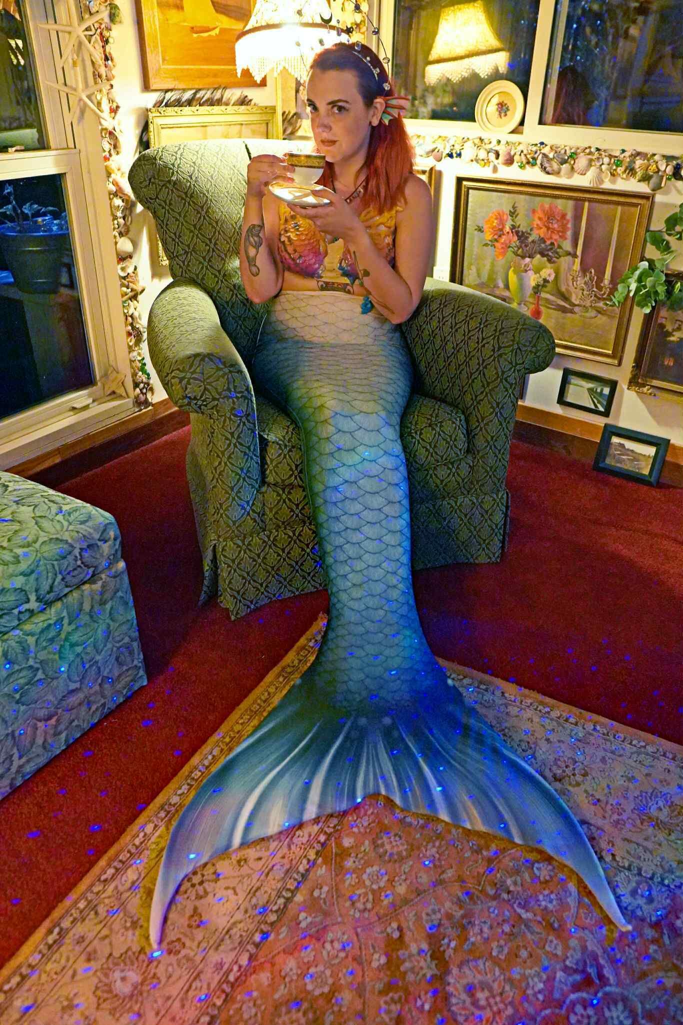 A mermaid costume in a room with patterned furniture and a red carpet.