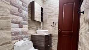 Un baño con inodoro, lavabo, tocador y una puerta.