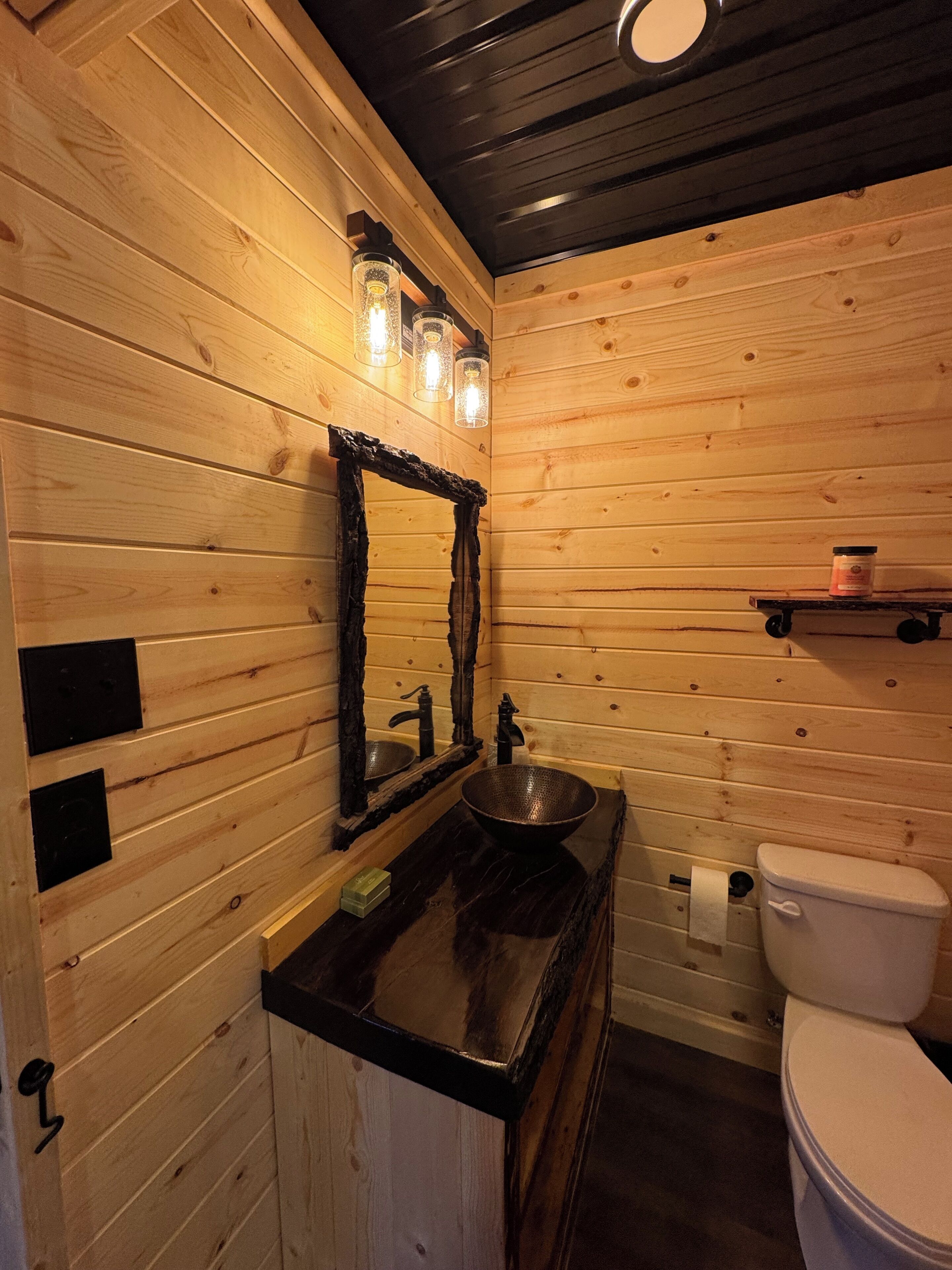 Ein Badezimmer einer Holzhütte mit Waschbecken, Spiegel und Toilette.