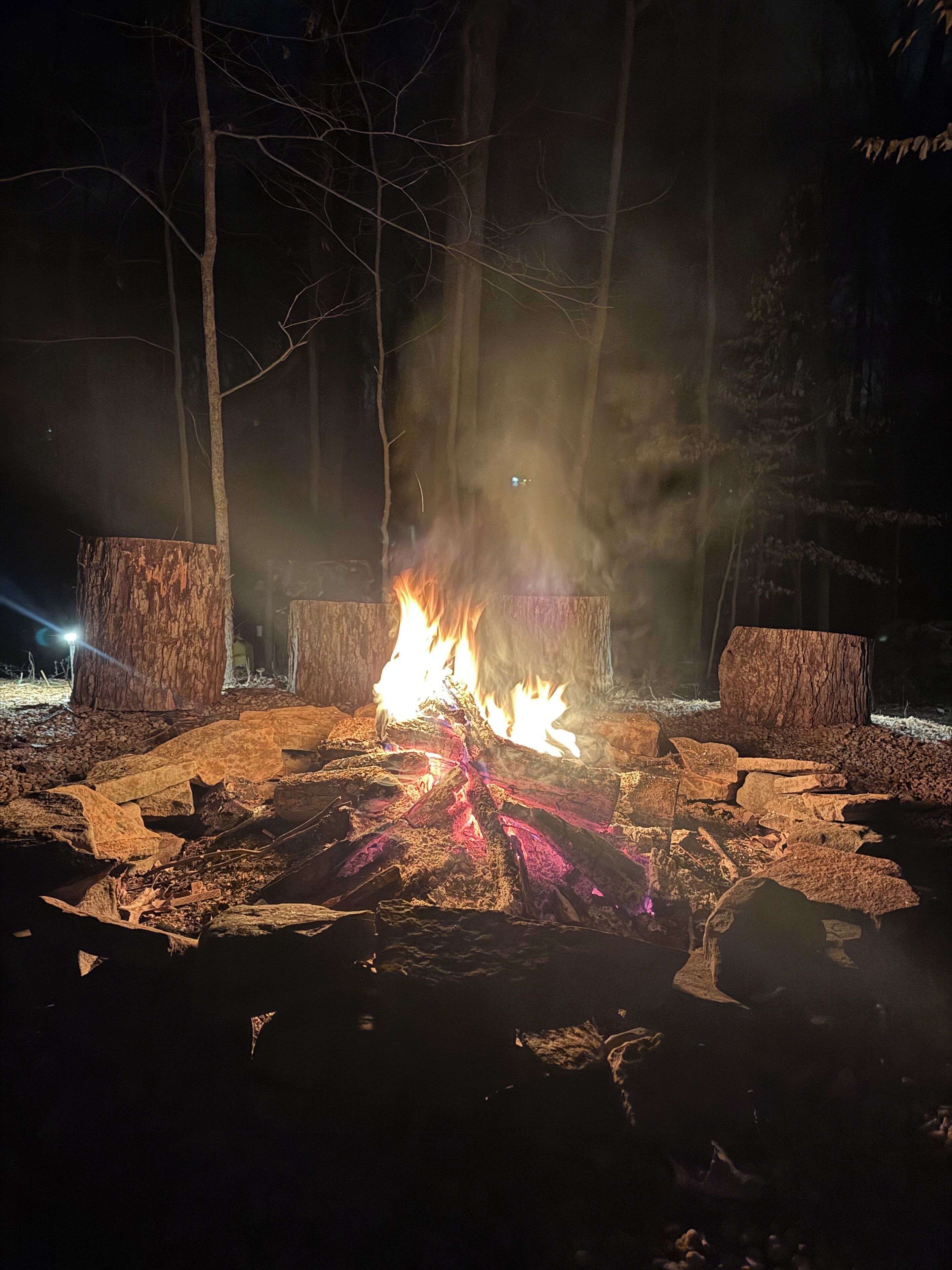Una fogata rodeada de rocas y árboles por la noche.