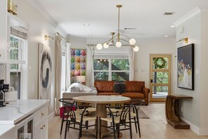 A modern kitchen with a dining area, a large window, and a view of the outdoors. - Zilker Home | Walk to Zilker/ACL/Barton Springs (Austin)