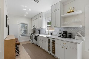 A modern kitchen with white cabinets, a built-in oven, a sink, and a coffee maker. - Zilker Home | Walk to Zilker/ACL/Barton Springs (Austin)