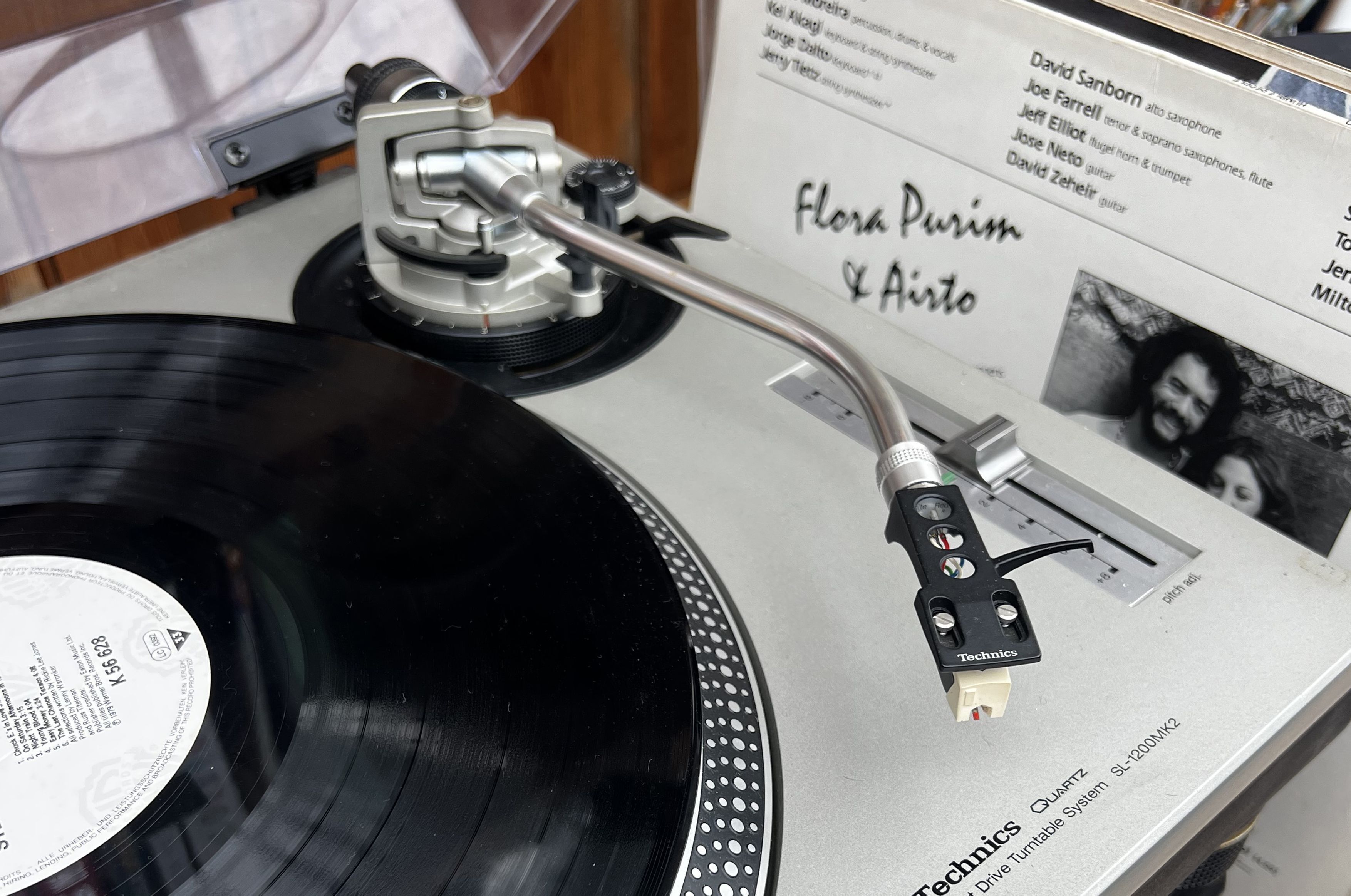 Une platine vinyle avec un disque, une aiguille et une étiquette sur laquelle on peut lire : « Flora Purim & Airot ».