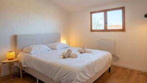 Un dormitorio con cama, lámparas de noche, ventana y radiador.