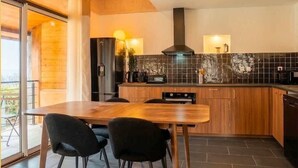 Una cocina moderna con una mesa y sillas de madera, estufa integrada y un ventanal grande.