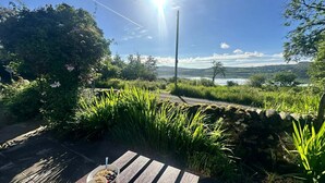 A wooden bench with a table, a bowl of cereal, and a mug. - Romantic Secluded Cosy Stone Cottage Beside the West Loch, Beautiful Argyll (Tarbert)