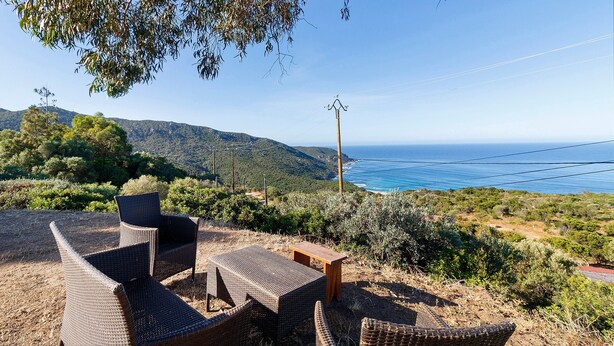 Outdoor wicker furniture, a wooden table, and a view of the ocean and hills. - Gîte Aja Puzzuta - Sea View (Coti-Chiavari)