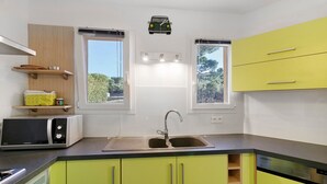 A kitchen with a microwave, sink, and green cabinets. - Gîte Aja Puzzuta - Sea View (Coti-Chiavari)