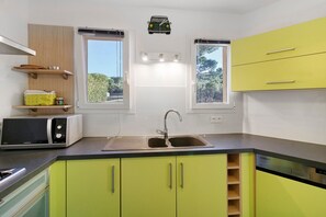 A kitchen with a microwave, sink, and green cabinets. - Gîte Aja Puzzuta - Sea View (Coti-Chiavari)