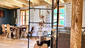 A wooden interior with a dining area, a sofa, and a hanging plant arrangement.
