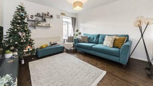 A living room with a teal sofa, a Christmas tree, a large rug, and a floor lamp. - Four-bedroom home in Chiswick, West London, near transport links (London)