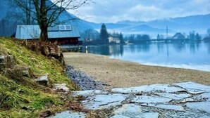 A lakeside view with a wooden dock, a small building, and mountains in the background. - SeeChalet Hallstatt (Bad Goisern am Hallstättersee)