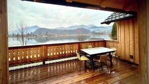 A wooden deck with a table and chairs, overlooking a lake and mountains. - SeeChalet Hallstatt (Bad Goisern am Hallstättersee)