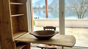 A wooden table with a bowl, a chair, and a view of a lake through a glass door. - SeeChalet Hallstatt (Bad Goisern am Hallstättersee)
