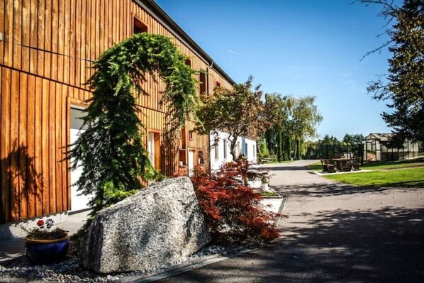 A wooden building with a large rock and a tree in front.