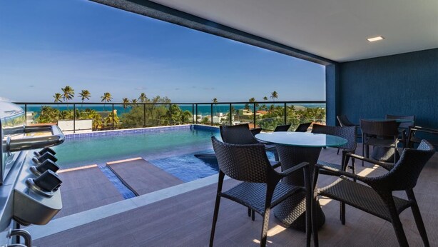 Un balcón con piscina, mobiliario exterior y vista al océano.