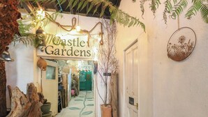 En smal gang med et skilt, der viser 'Castle Gardens', der fører til en grøn dør.