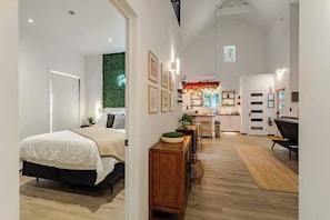 Ein modernes Hotelzimmer mit Bett, kleinem Schreibtisch, Küchenzeile und Wohnbereich.