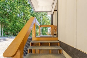 Eine Holztreppe führt zu einem überdachten Außenbereich mit Blick auf Bäume.