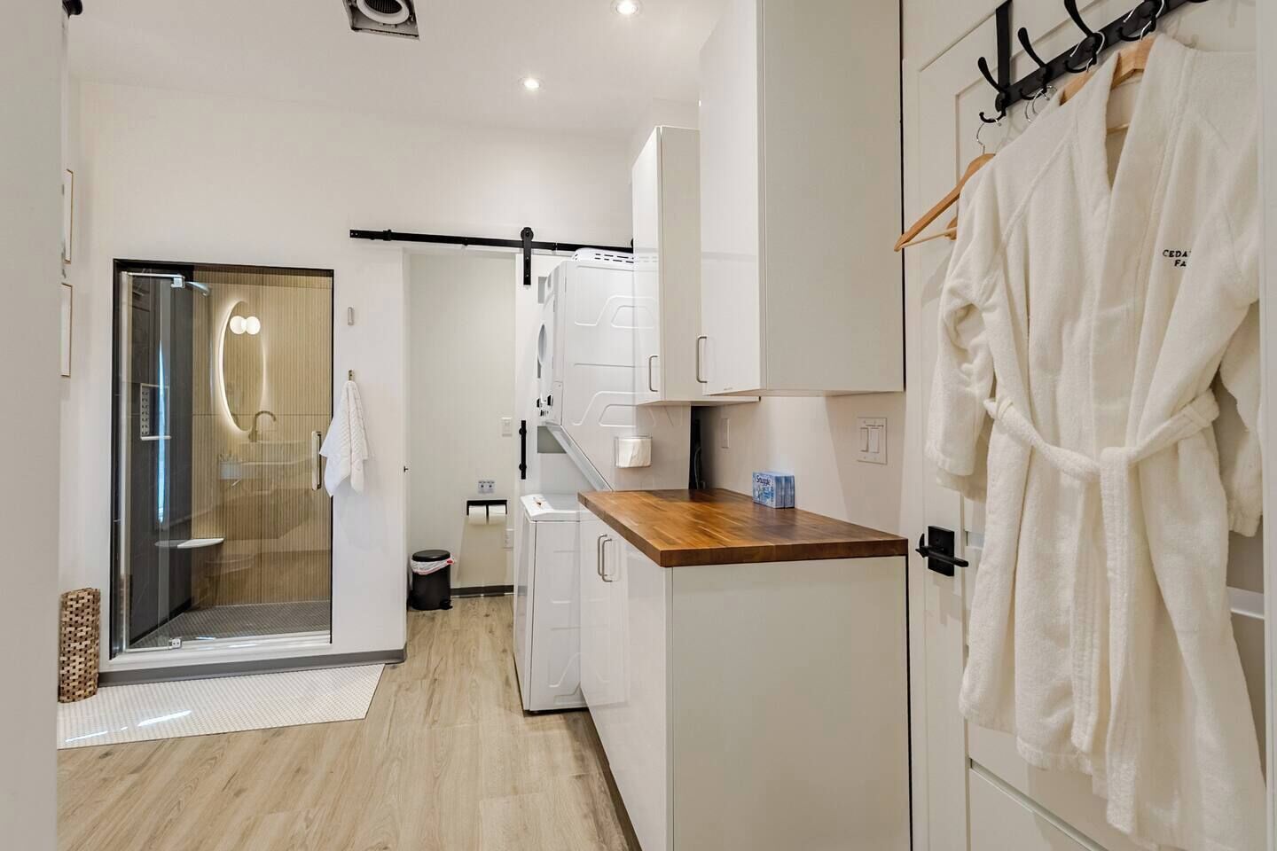 A modern kitchen with white cabinets, a wooden countertop, and a hanging robe.