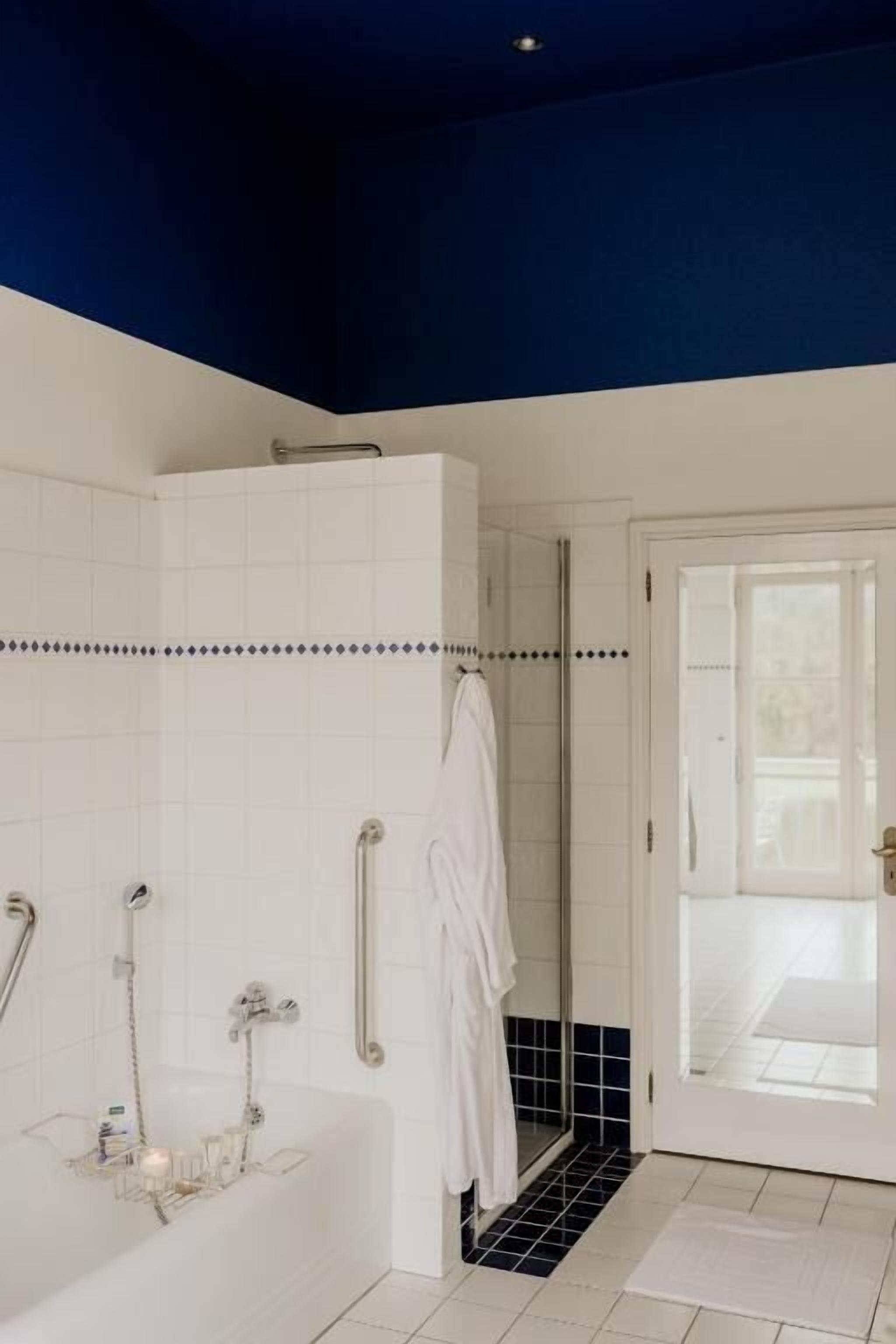 Een badkamer met een bad, douche en een glazen deur naar een balkon.