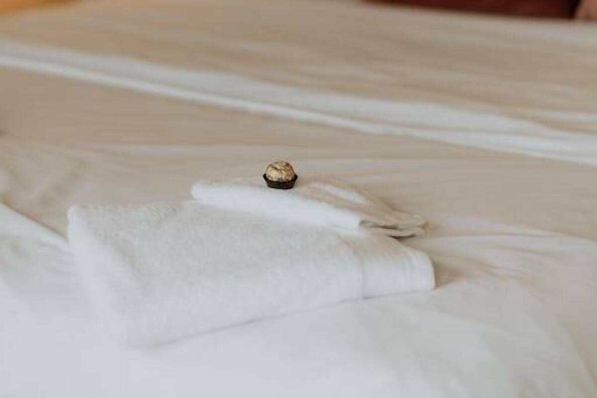 A bed with a white comforter, a ring, and a folded towel.