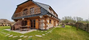 Een houten chalet met een balkon, een pad van stenen en tuinmeubilair.