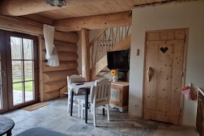 A rustic wooden interior with a dining table, chairs, a TV, and a heart-shaped door. - Comfortable Apartment With Terrace, Close to Beach (gmina Będzino)