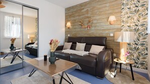 Una sala moderna con un sofá de cuero, una mesa de centro, un espejo y una pared con un diseño de hojas.