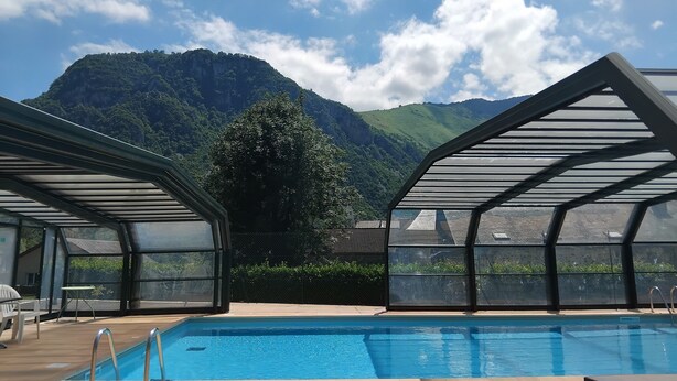 Zona de piscina con vista a la montaña, asientos cubiertos y piscina cercada.