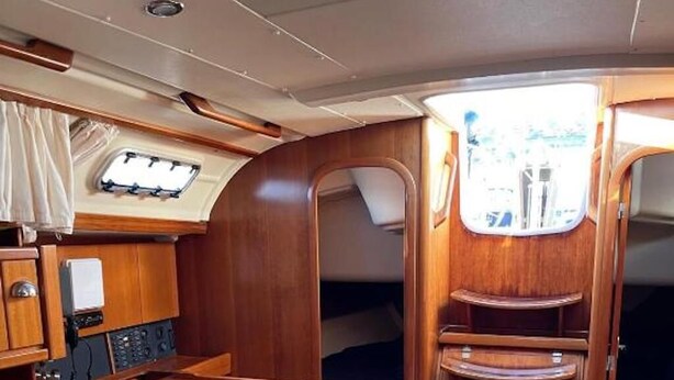 Un interior compacte amb una taula de fusta, una cadira amb almoçó, un panell de control i una zona amb lliteres.