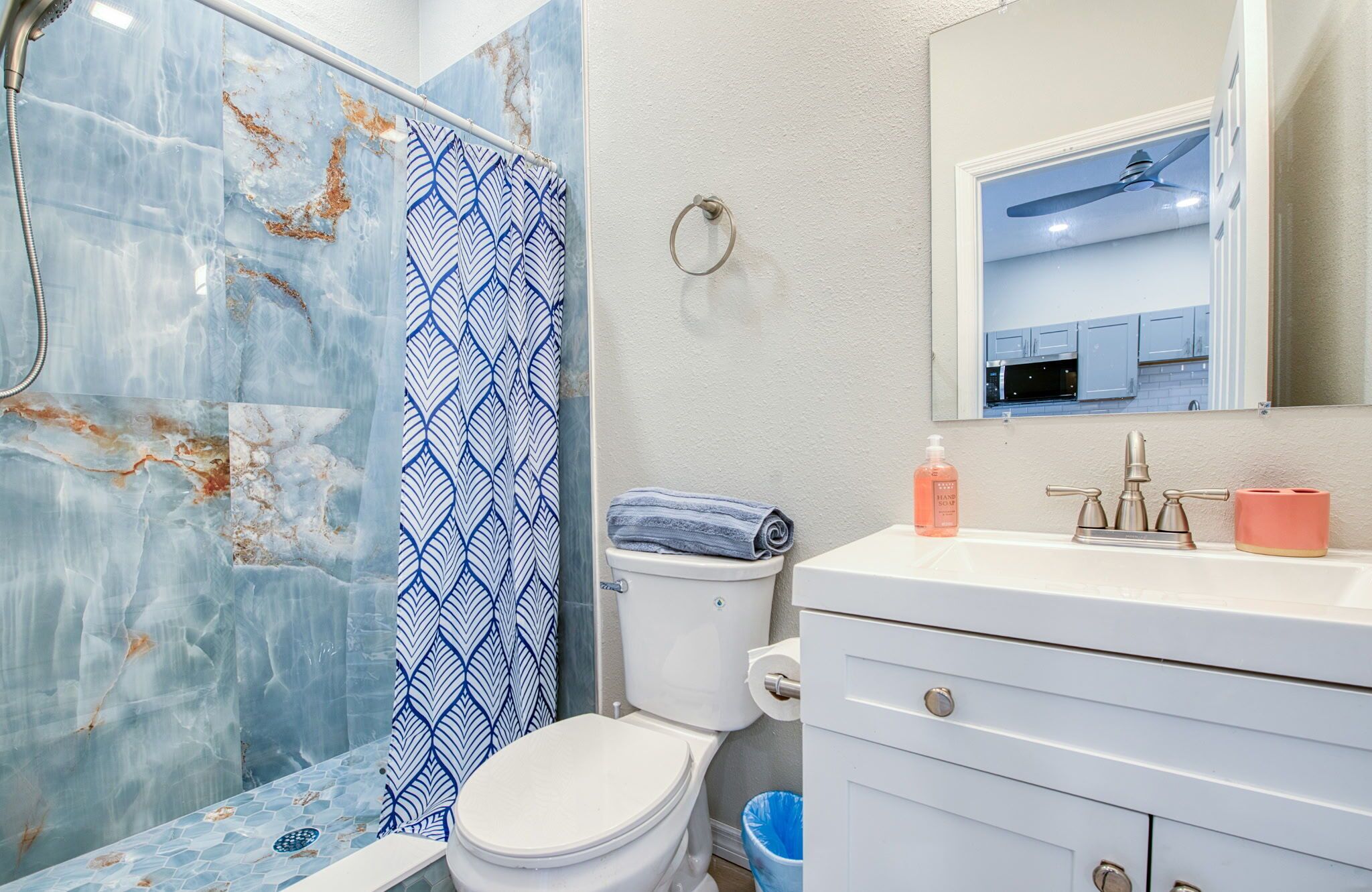 A bathroom with a shower, toilet, sink, and mirror.
