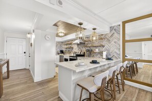 Eine moderne Küche mit einer Kochinsel, Barhocker und Pendelleuchten.