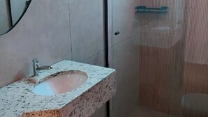 A bathroom with a granite sink, a mirror, and a towel rack. - Pousada Finca dos Anjos (Passa Quatro)
