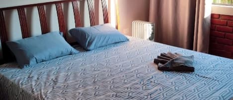 A bed with a patterned bedspread, two pillows, and a blanket folded at the foot of the bed.