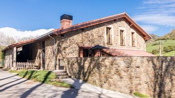 A stone building with a red roof, a wooden fence, and a clear sky.