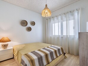 Makuuhuone, jossa on sänky, yöpöytä, lamppu ja ikkuna, jossa on verhot.