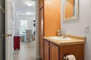 A bathroom with a wooden vanity, a sink, and a mirror. - The Beacon at Barefoot (Wells)