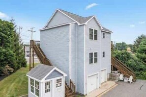 A two-story house with a garage, a small attached shed, and a staircase leading to the garage. - The Beacon at Barefoot (Wells)