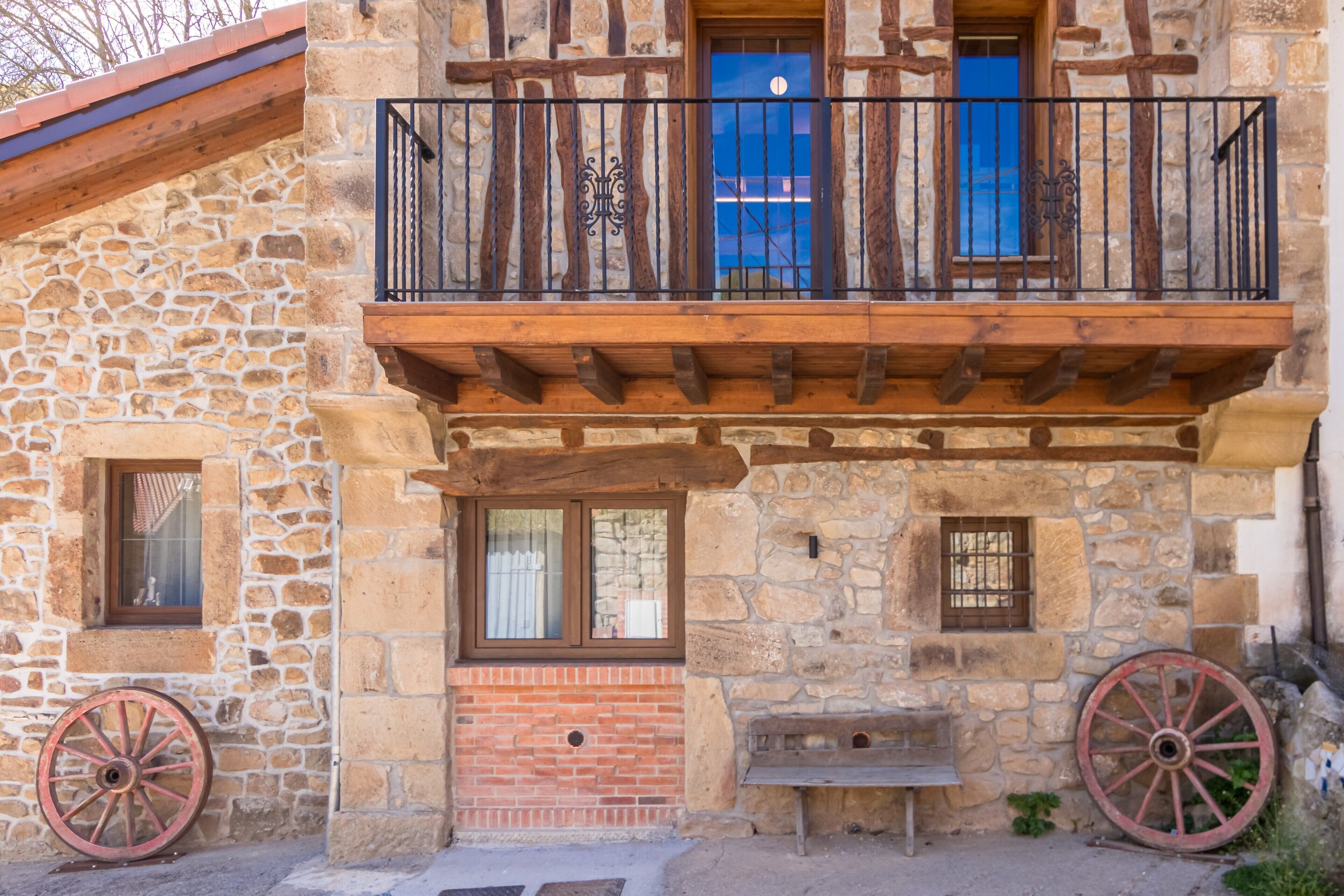 Ein Steinhaus mit Balkon, Holzbalken und einer Bank.
