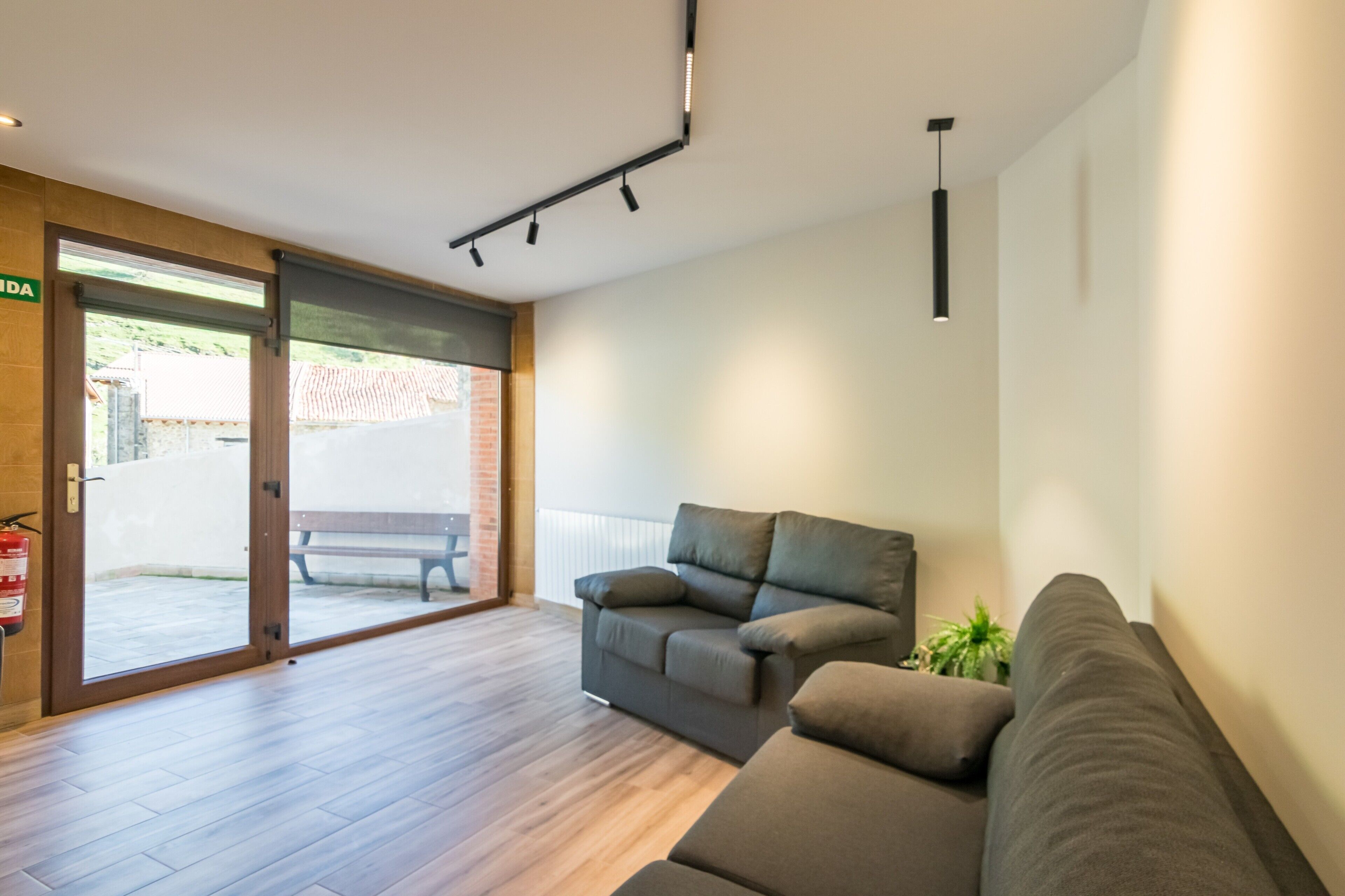 Un salon moderne avec un canapé, un banc et une porte donnant sur un espace extérieur.